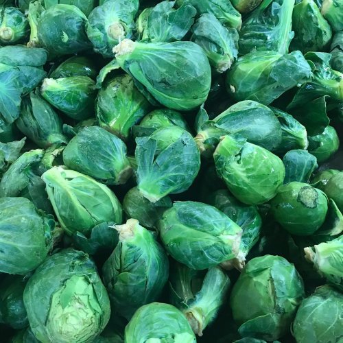 A close-up of fresh, green Brussels sprouts piled together.