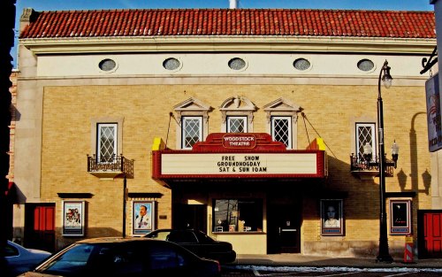 Historic Woodstock Theatre with a marquee advertising a free show, featuring decorative windows and a red-tiled roof.