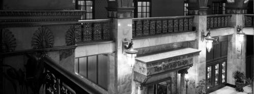 Black and white image of an elegant interior with ornate architecture, featuring balconies and decorative lighting.