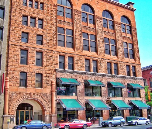 Historic building with ornate stonework and large windows, featuring green awnings and classic architectural details.