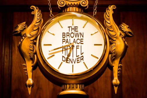 A vintage clock featuring the text "The Brown Palace Hotel Denver," adorned with decorative golden pegasus figures.