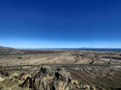 A panoramic view of a vast desert landscape with mountains in the distance under a clear blue sky.