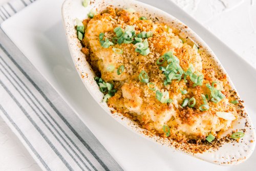 Baked dish topped with breadcrumbs and green onions, served on a white plate with a striped napkin.