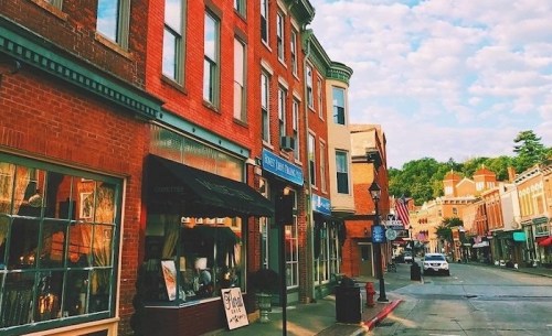 Charming street view of brick buildings and shops under a blue sky with scattered clouds.