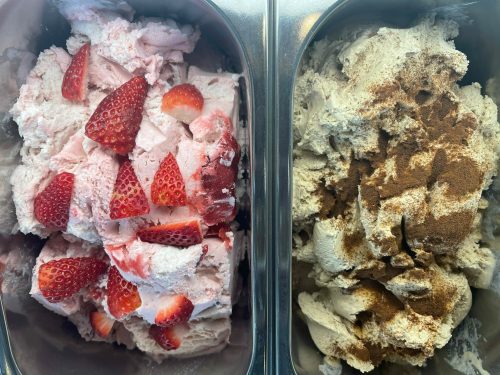 Two containers of ice cream: one with strawberry ice cream topped with fresh strawberries, and the other with a cinnamon flavor.