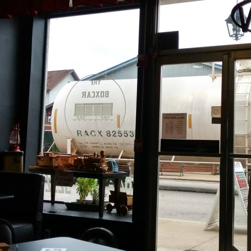 View from inside a café showing a large white tank outside, with a sign reading "The Boxcar" visible.