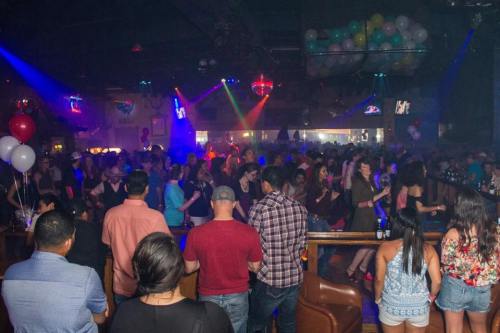 A crowded nightclub scene with colorful lights, people dancing, and a lively atmosphere.