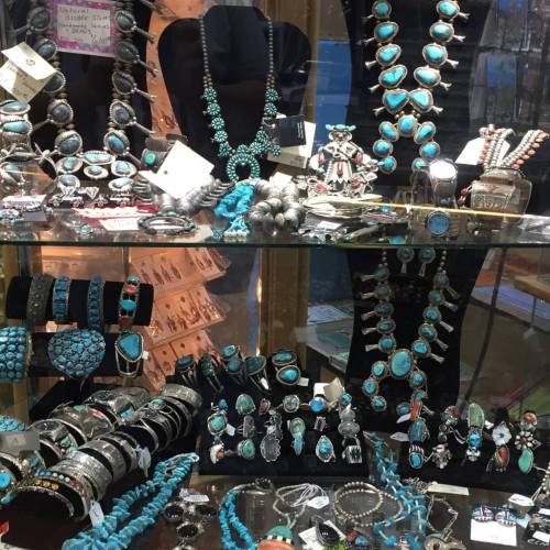 A display case filled with various turquoise jewelry, including necklaces, bracelets, and rings.