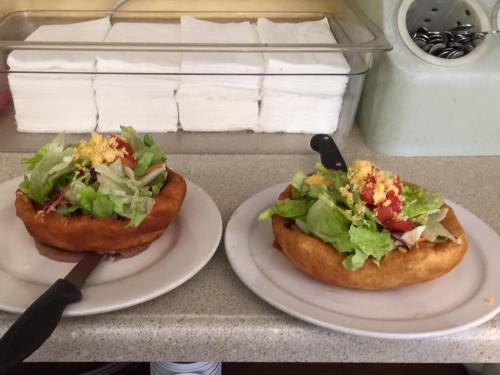 Two large, crispy taco bowls filled with fresh salad and topped with crumbled cheese, served on white plates.