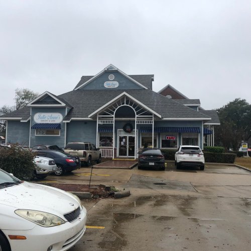 A blue building with a sign reading "Julie Anne's" and parked cars in front, on a cloudy day.