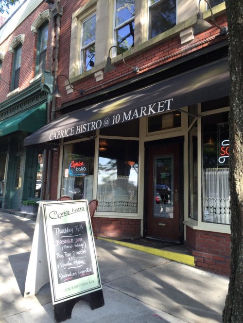 Exterior of Caprice Bistro with a signboard displaying daily specials and a canopy over the entrance.