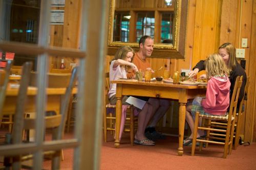 A family of four enjoys a meal together at a wooden table in a cozy, rustic dining room.