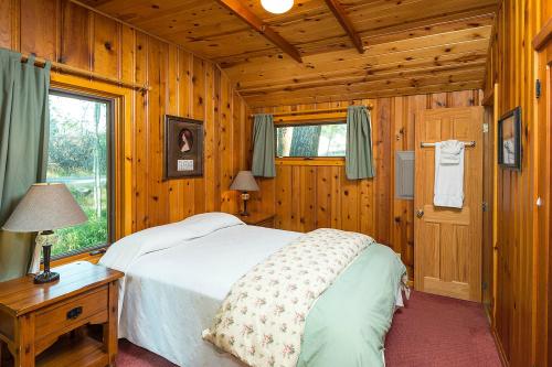 Cozy wooden bedroom with a double bed, lamps, and green curtains, featuring rustic decor and a warm atmosphere.
