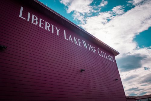 A purple building with the text "Liberty Lake Wine Cellars" against a cloudy sky.