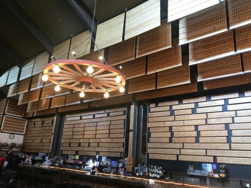 Interior of a bar featuring a wooden wall design, a circular chandelier, and a long bar counter.