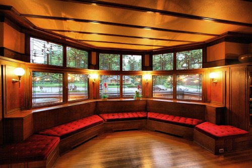 Cozy interior with curved wooden seating, large windows, and warm lighting, creating an inviting atmosphere.