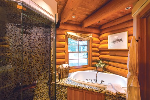 Cozy log cabin bathroom featuring a stone shower, a jetted tub, and natural wood accents.