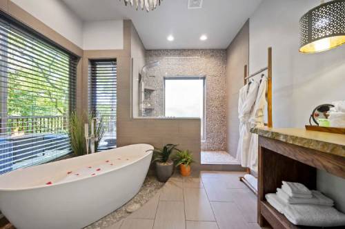 A modern bathroom featuring a freestanding tub, a walk-in shower, and natural light from large windows.