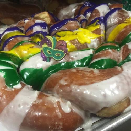 Colorful king cakes decorated with icing and a small mask, celebrating Mardi Gras festivities.