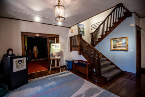 A welcoming entryway with a staircase, art on the walls, and a sign reading "Welcome Back" at the Bob Ross studio.