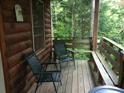 A wooden porch with two green chairs, surrounded by trees and nature.