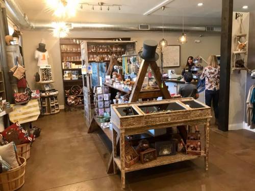 A cozy shop interior featuring rustic decor, shelves of merchandise, and customers at the counter.