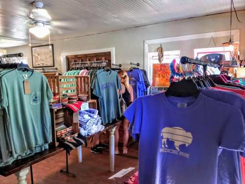A colorful display of t-shirts in a shop, with a customer browsing in the background.