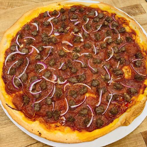 A freshly baked pizza topped with pepperoni, ground beef, and red onion on a golden crust.