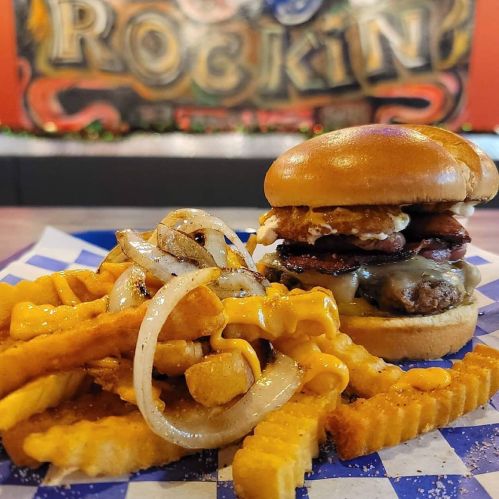 A delicious burger with bacon and cheese, served with crinkle-cut fries topped with melted cheese and grilled onions.