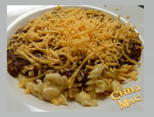 A plate of chili mac topped with shredded cheese, featuring spiral pasta and a hearty chili sauce.
