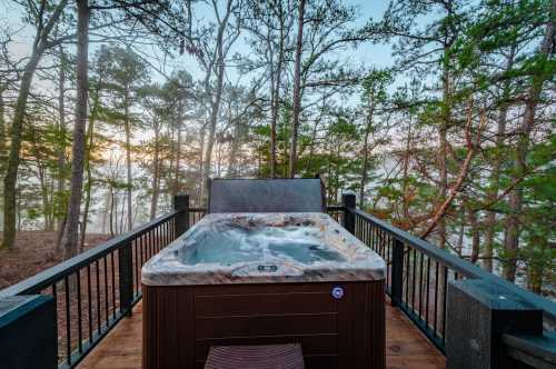 A hot tub on a wooden deck surrounded by trees, with misty scenery in the background at sunrise.