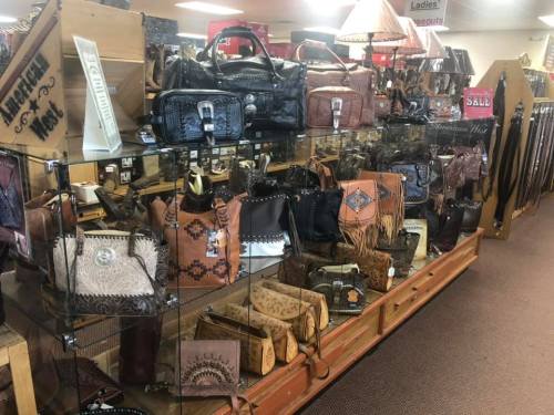 Display of various leather handbags and accessories in a store, featuring different styles and designs.