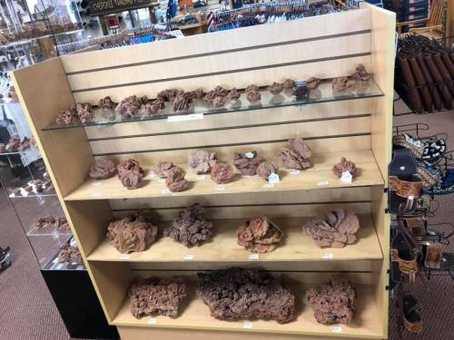 Display of various natural rock formations on wooden shelves in a store.
