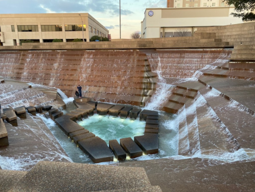 A modern water feature with cascading waterfalls and a central pool, surrounded by geometric stone structures.