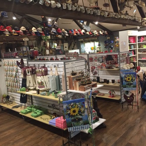 A cozy gift shop interior featuring shelves of merchandise, hats, mugs, and decorative items in a rustic setting.