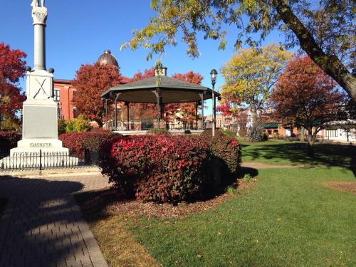 A park scene featuring a gazebo surrounded by colorful autumn foliage and a clear blue sky.