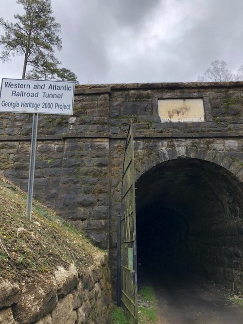 Entrance to the Western and Atlantic Railroad Tunnel, featuring a stone archway and a sign about the Georgia Heritage 2000 Project.