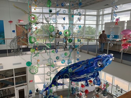 A colorful art installation featuring a large blue whale and various sea-themed decorations in a bright, open space.