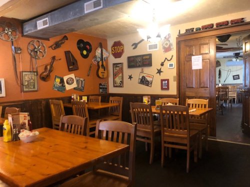 Cozy restaurant interior with wooden tables, chairs, and vintage decor on the walls, including musical instruments and signs.