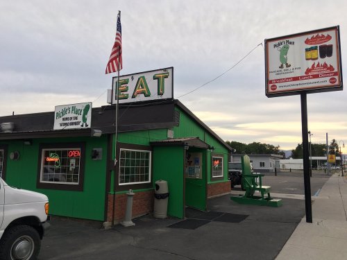 Exterior of Pickle's Place restaurant with a green facade, open sign, and an American flag.
