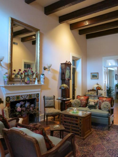 Cozy living room with vintage furniture, a large mirror, decorative fireplace, and warm lighting.