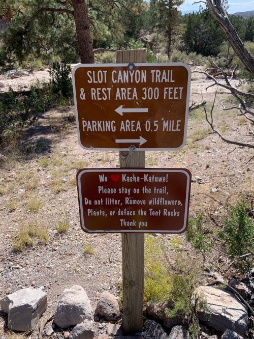 Signpost indicating directions to Slot Canyon Trail and parking area, with a message about preserving nature.