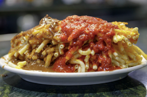 A plate of macaroni topped with two sauces: one brown and one red, creating a colorful and hearty dish.