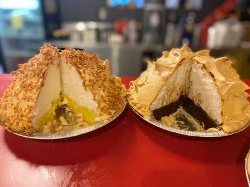 Two pie halves on a red counter: one with coconut topping and yellow filling, the other with caramel topping and chocolate filling.