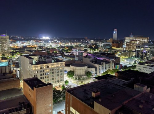 A nighttime cityscape view showcasing illuminated buildings and streets in an urban area.