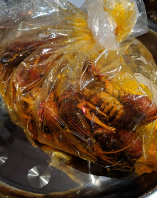 A sealed plastic bag filled with marinated seafood, showcasing vibrant colors and spices.