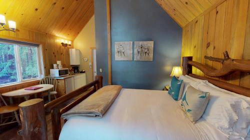 Cozy cabin interior featuring a bed, dining area, and wooden accents, with natural light from a window.