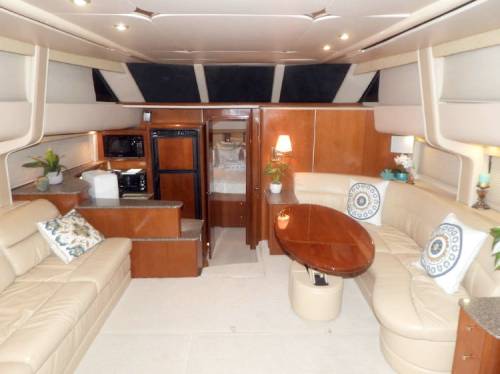 Interior of a yacht featuring a spacious lounge area with leather seating, a wooden table, and modern amenities.