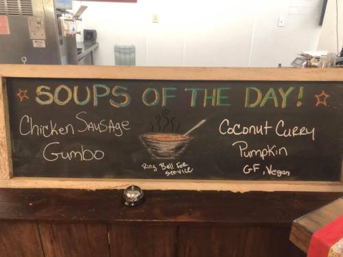 Chalkboard menu displaying "Soups of the Day": Chicken Sausage Gumbo and Coconut Curry Pumpkin, labeled GF Vegan.