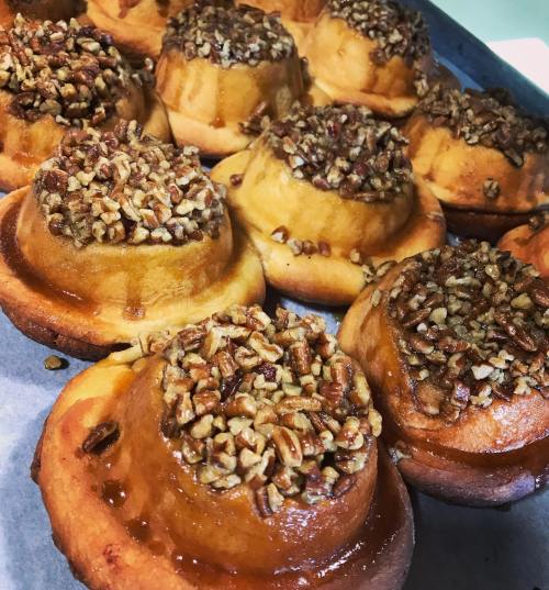 Freshly baked pecan sticky buns with a golden-brown glaze and a generous topping of chopped pecans.